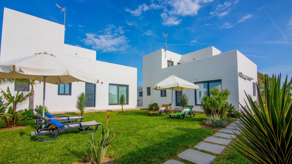 Vivienda blanca con jardín y zona de descanso exterior
